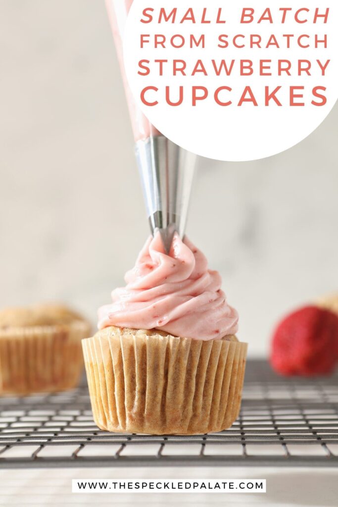 Strawberry Cream Cheese Frosting is swirled on top of a Strawberry Cupcake on a wire cooling rack with the text 'small batch from scratch strawberry cupcakes'