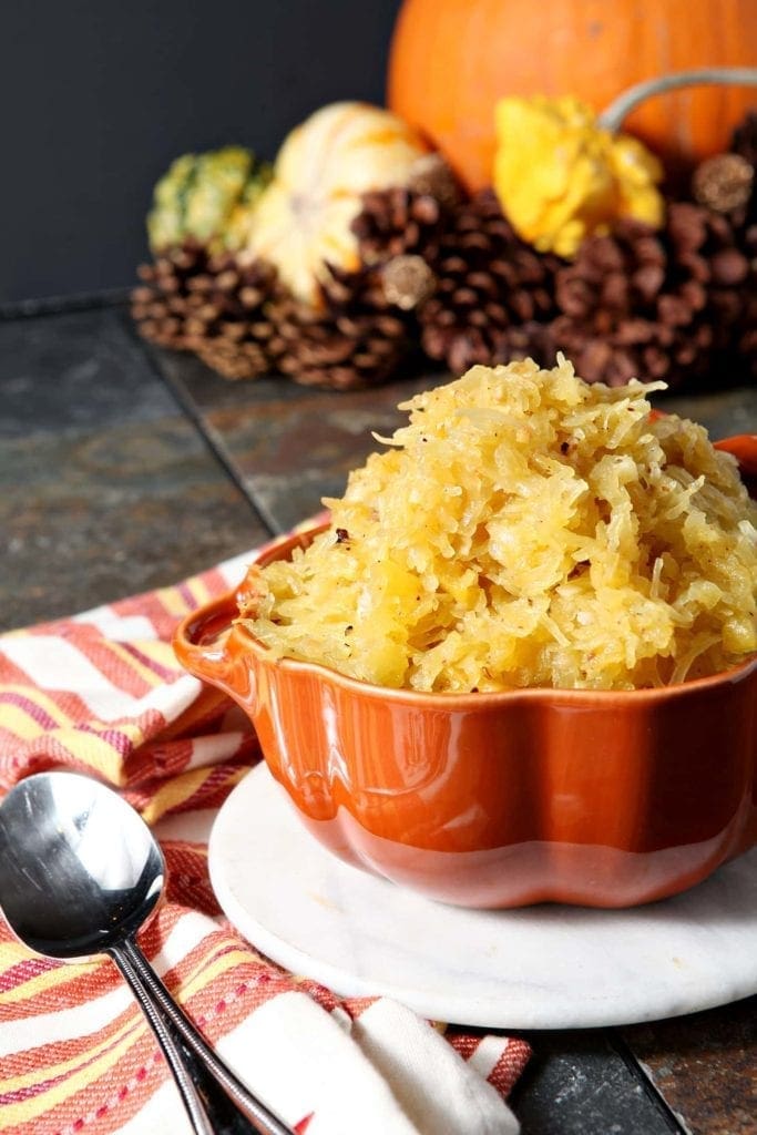 Orange bowl filled with garlicky spaghetti squash on linens 