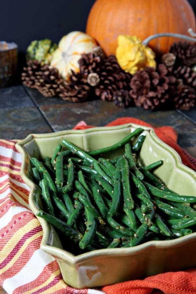 Lemon Pepper Green Beans in serving dish in front of pumpkin décor 