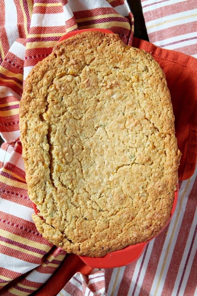 Overhead of a red baking dish sitting on red and orange striped towels holding a cornbread casserole