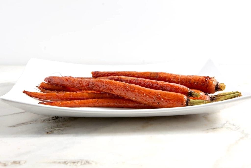 Honey Roasted Whole Carrots laying on a white platter 