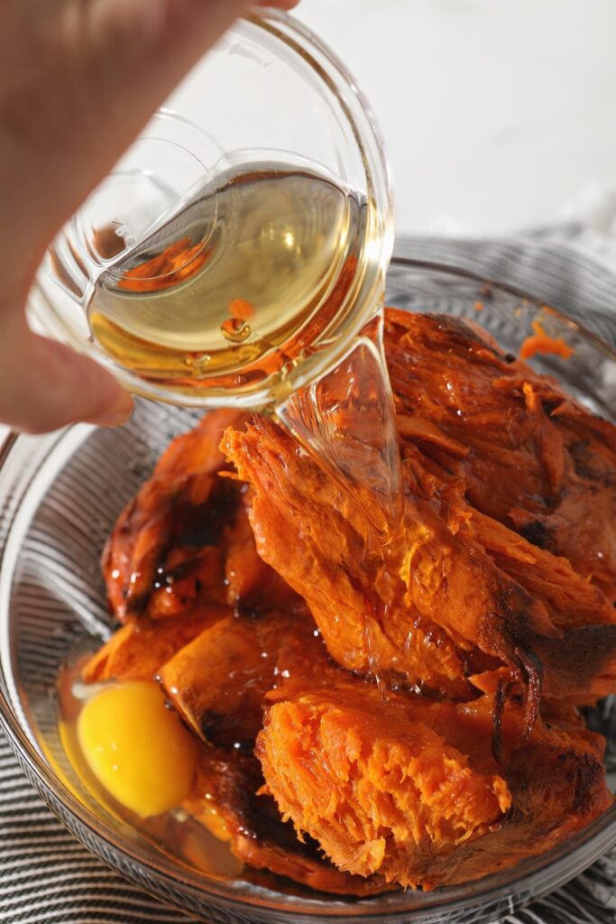 Bourbon is poured on top of sweet potatoes and other ingredients in a bowl