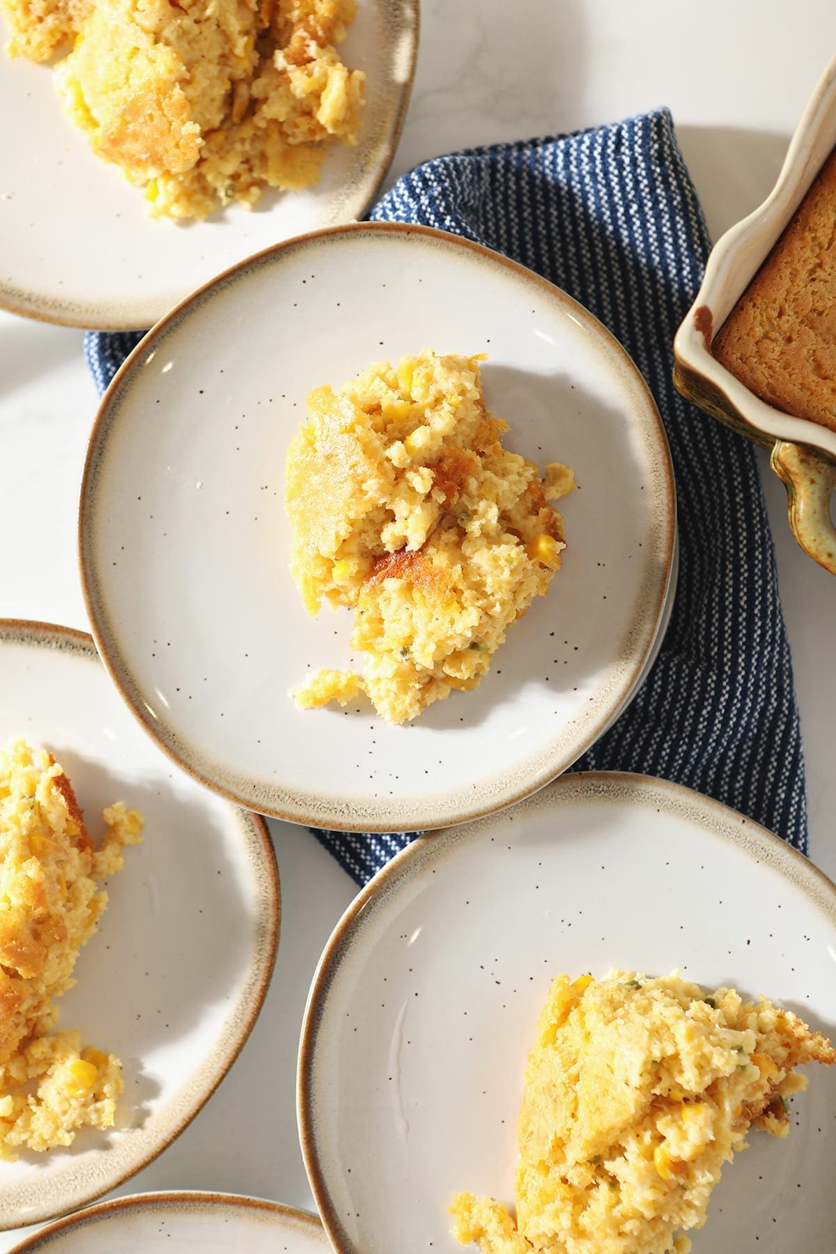 A white plate holds a scoop of Creamed Cornbread Casserole