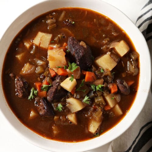 Close up of a bowl of slow cooker beef stew on a marble surface