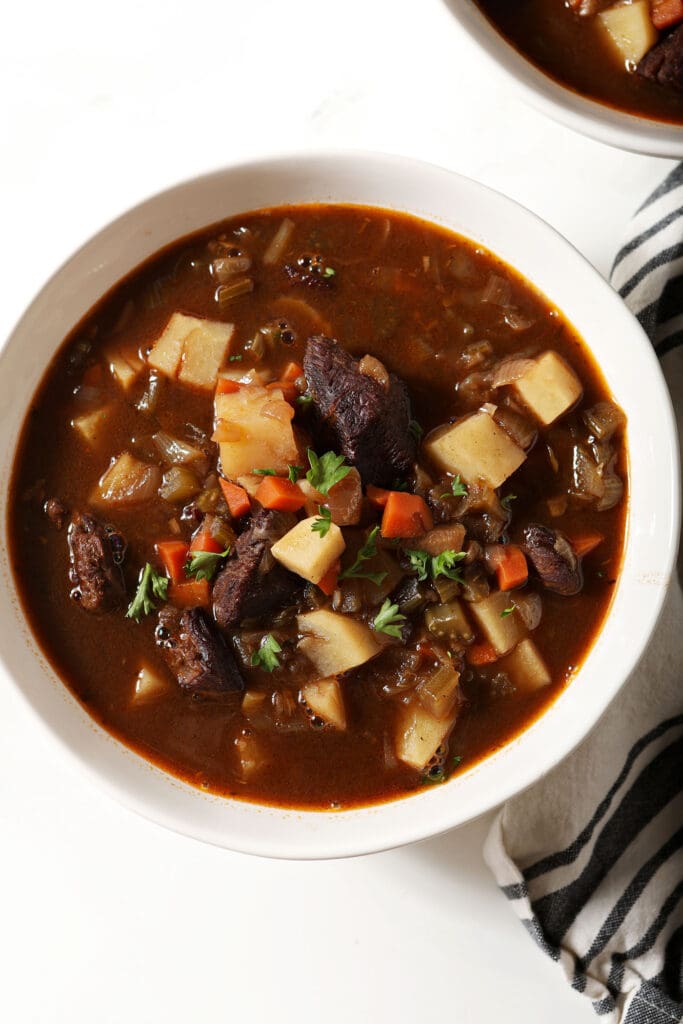 Close up of a bowl of slow cooker beef stew on a marble surface