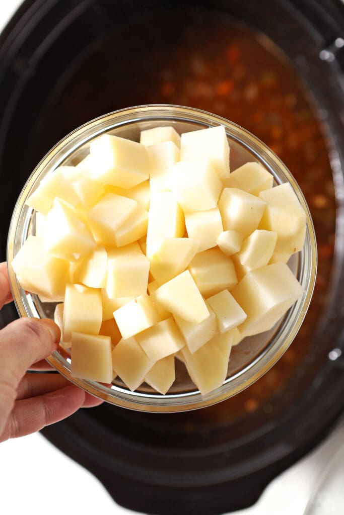 Chopped potatoes in a bowl over a slow cooker