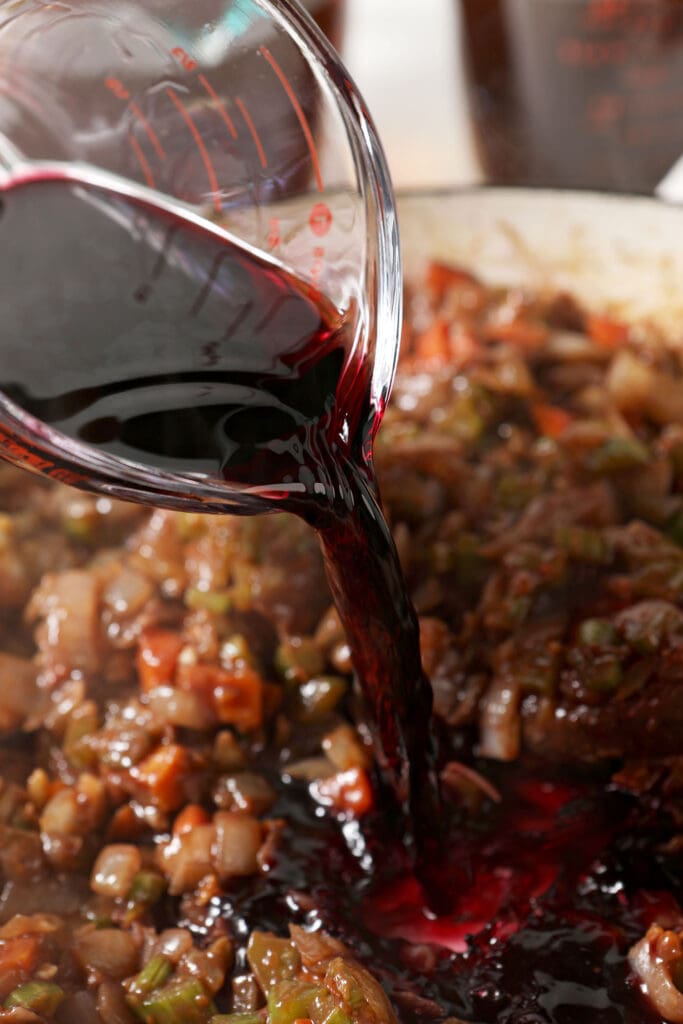 Wine pours into a skillet with veggies