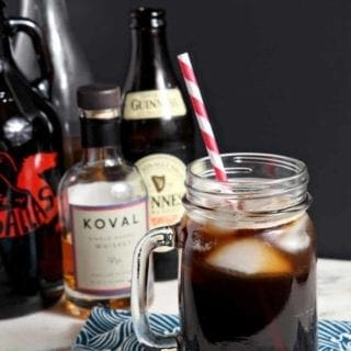 The Boyfriend Irish Coffee photographed on a light marble surface with a black background, surrounded by its ingredients