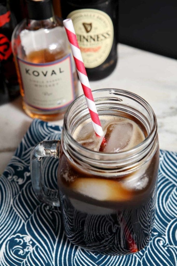 The Boyfriend Irish Coffee shown on a light marble surface with a black background, surrounded by its ingredients