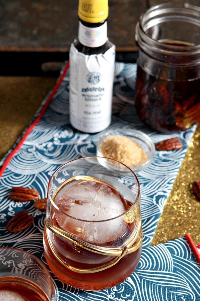 A glass holding a Toasted Pecan Old Fashioned sits on a tray, ready for drinking.