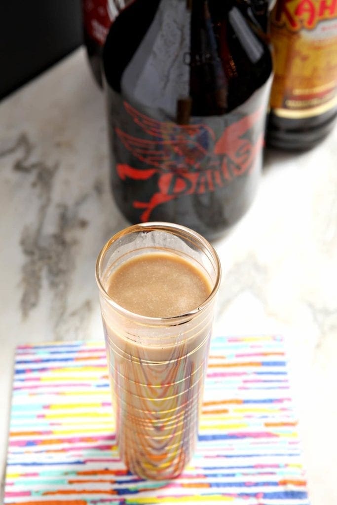 Overhead angled view of coffee drink on napkin in front of bottles 