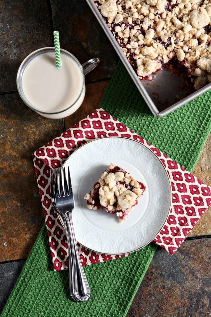 Cranberry Crumb Bar on white plate with fork and glass of milk 