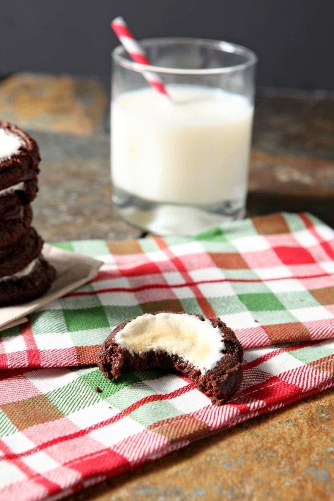 A bite out of cookie sitting on holiday linens with glass of milk
