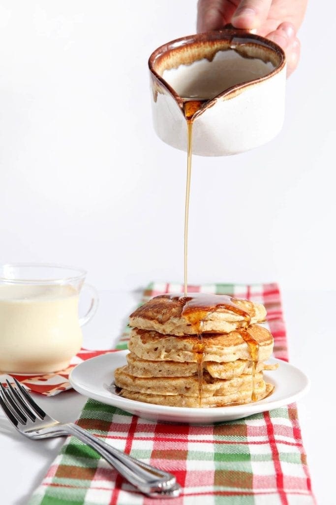 Cinnamon syrup is poured on top of a stack of Eggnog Pancakes