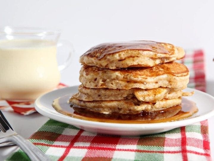 Cinnamon Syrup runs down the sides of a stack of pancakes sitting on a red and green plaid towel