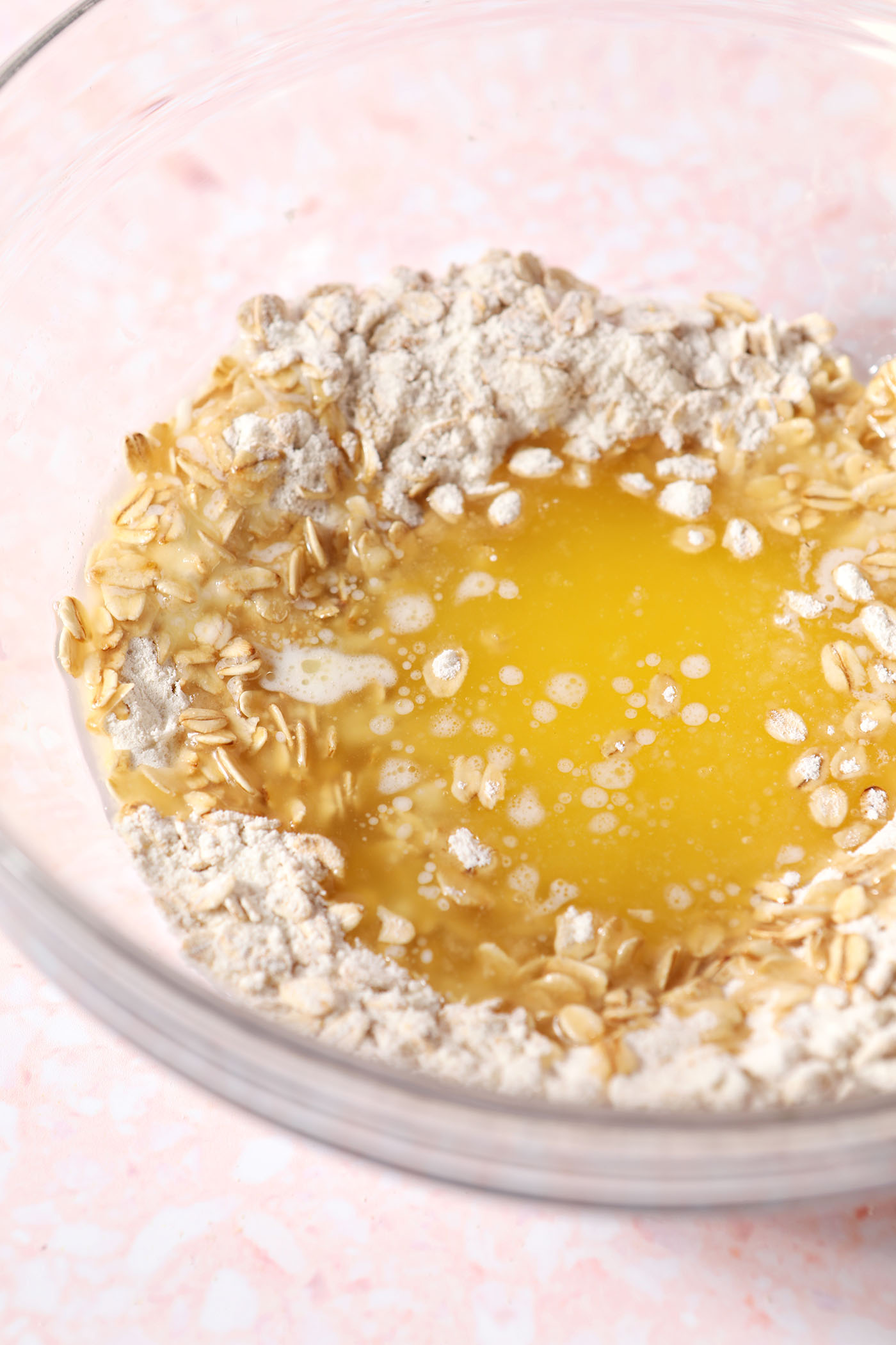 Melted butter on top of dry ingredients for a crumble topping in a glass bowl