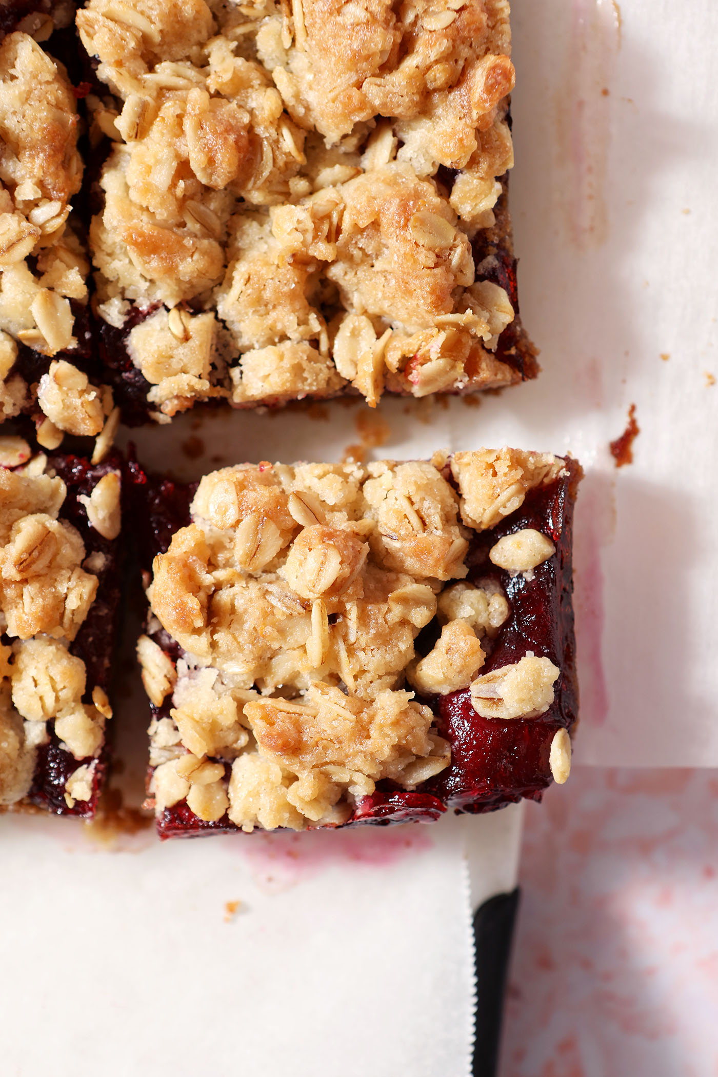 Close up of sliced cranberry bars with a crumble topping on a cutting board