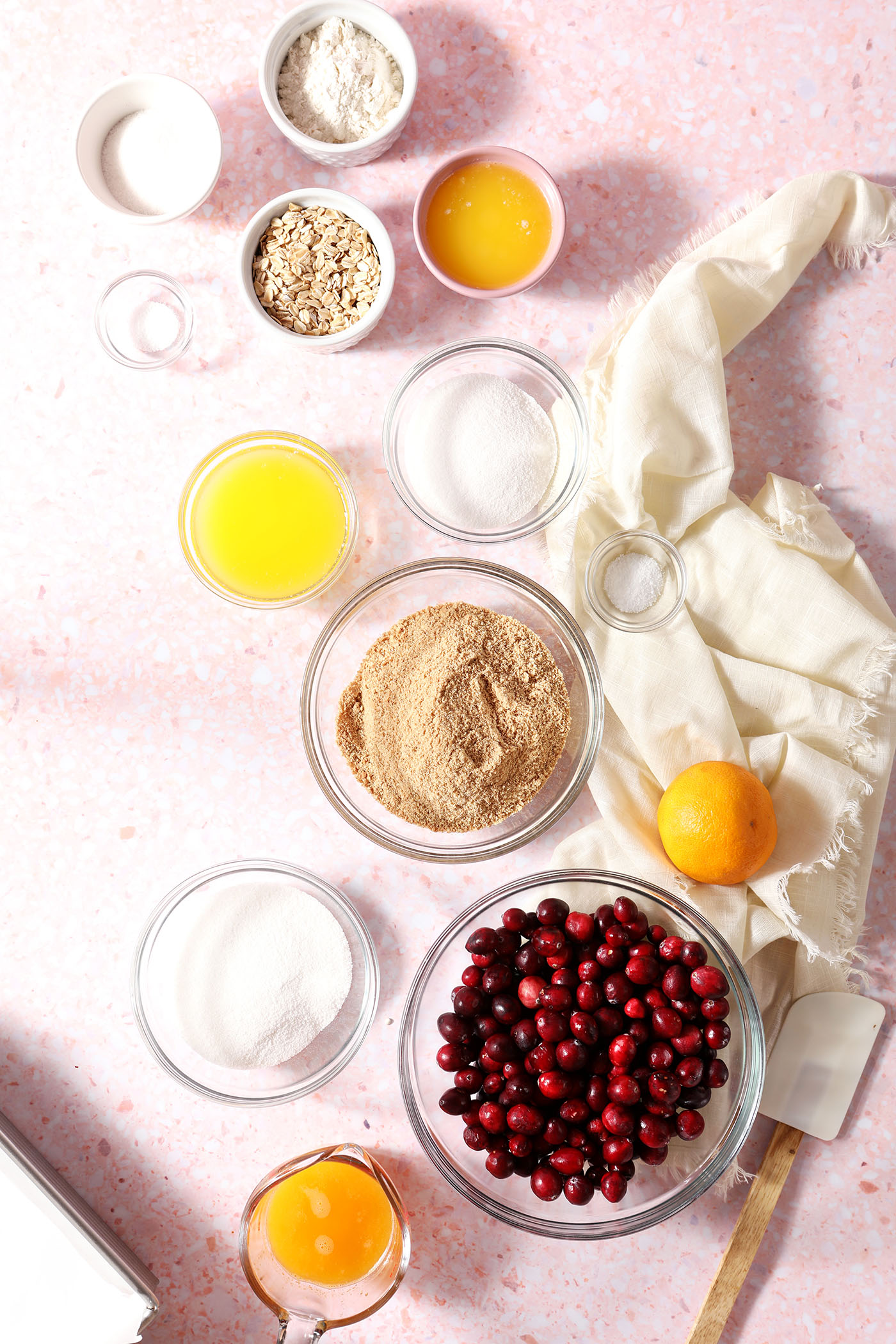 Ingredients to make cranberry bars in bowls on a pink surface