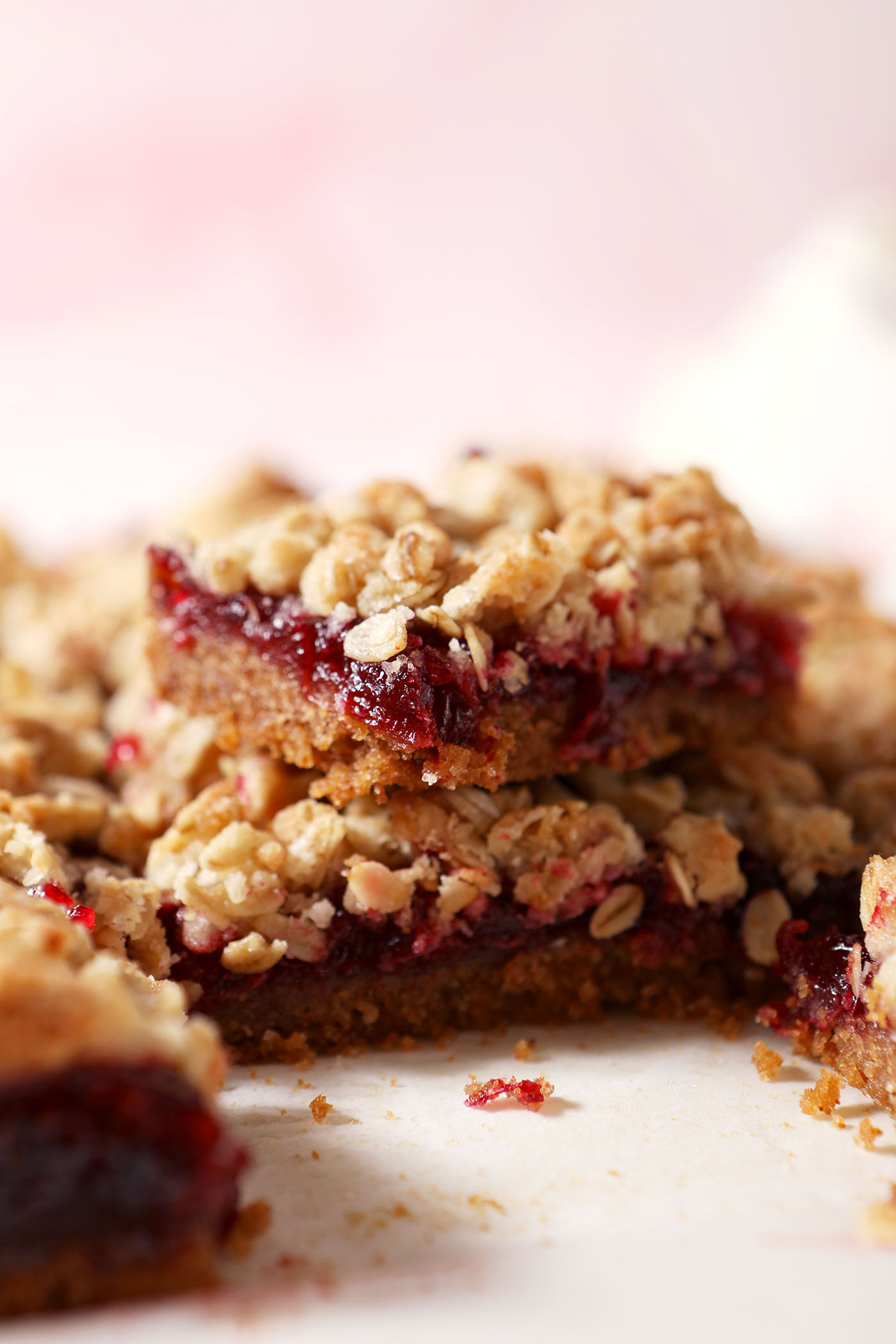 Cranberry bars stacked on top of each other on a cutting board with more bars