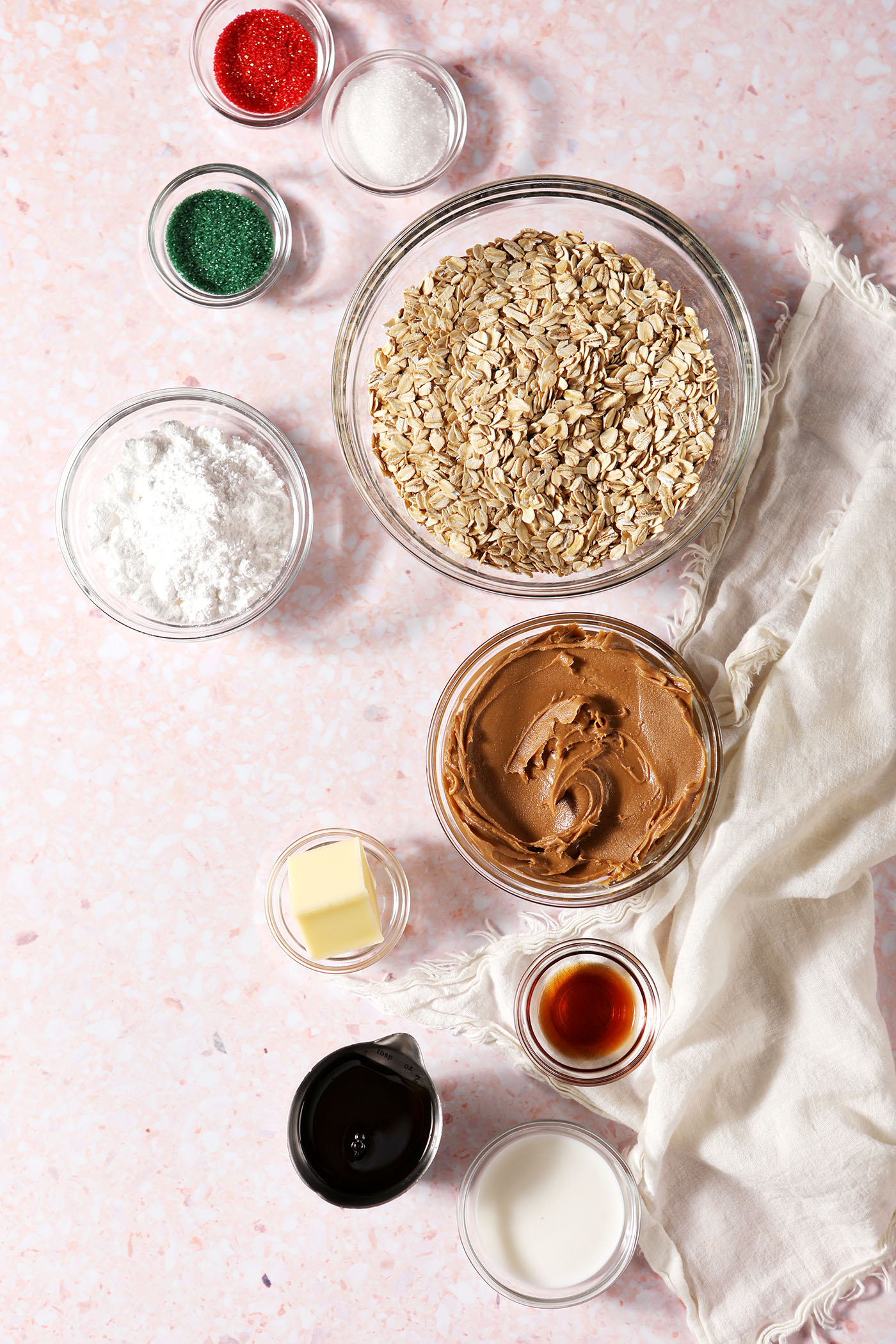 Ingredients to make no bake cookie butter cookies in bowls on a pink terrazzo surface next to a white linen