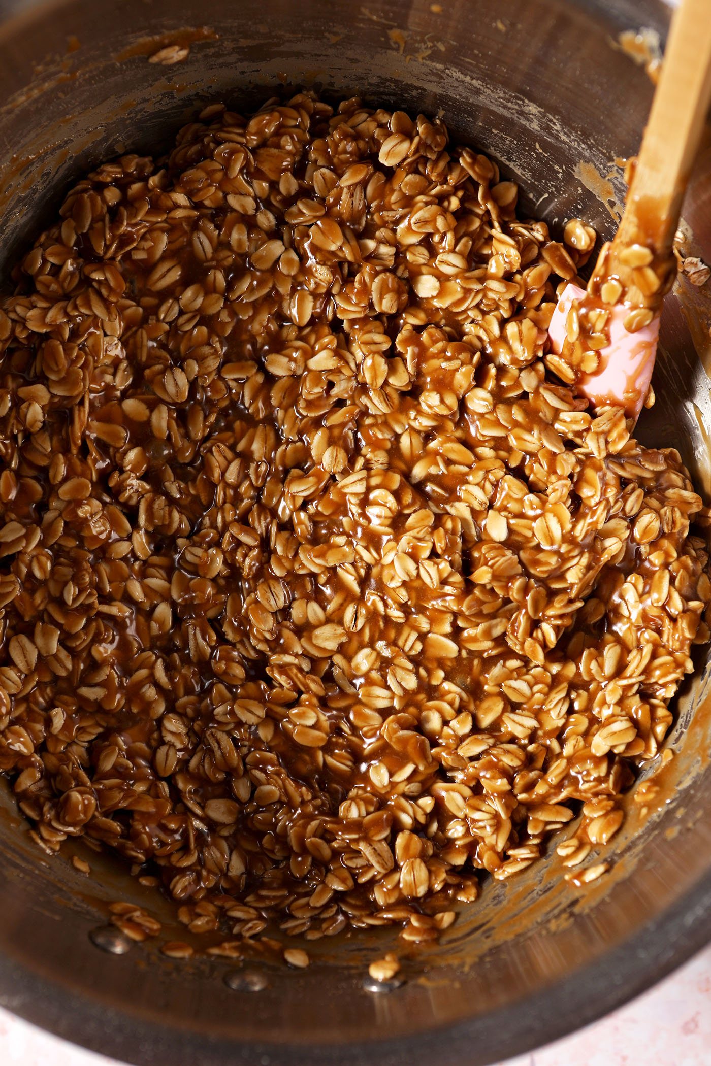 Mixed no bake cookie butter cookie batter in a silver saucepan with a rubber spatula