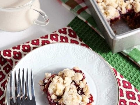 Cranberry crumb bar on plate with milk and baking pan