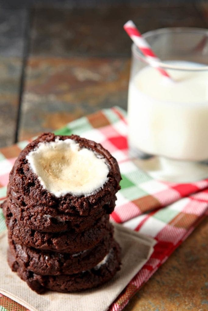 Stack of cookies on linens next to glass of milk 