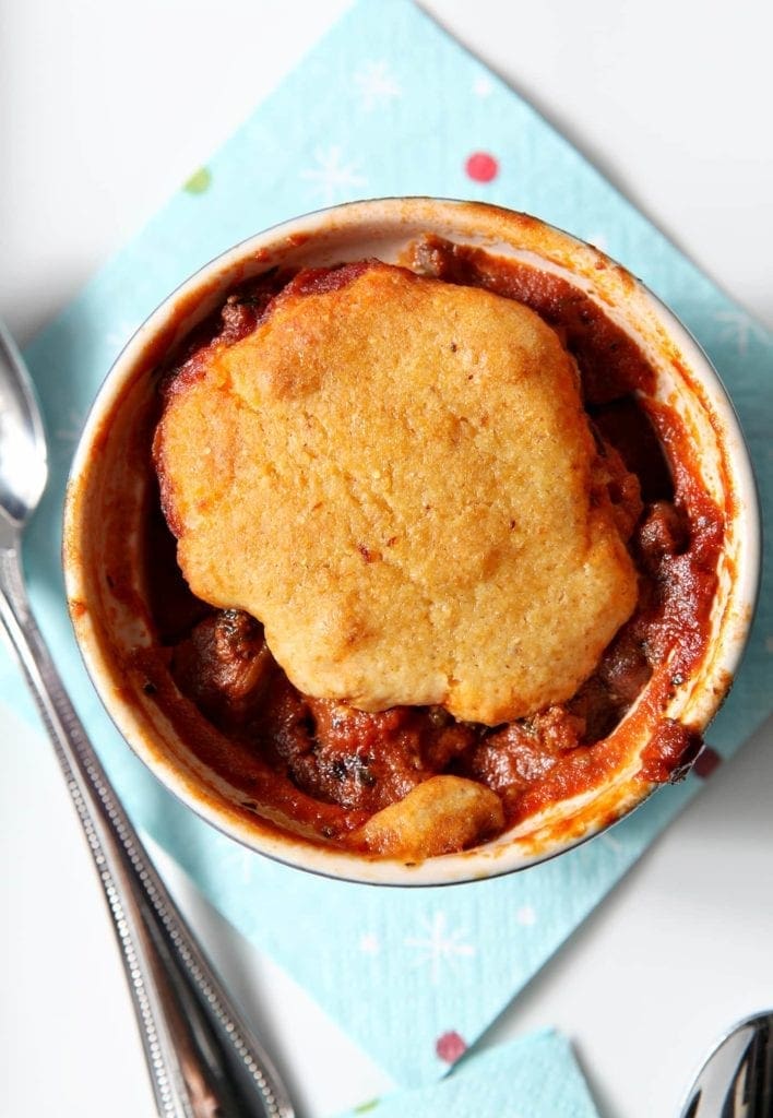 Close up of cornbread sitting on top of bowl of chili 