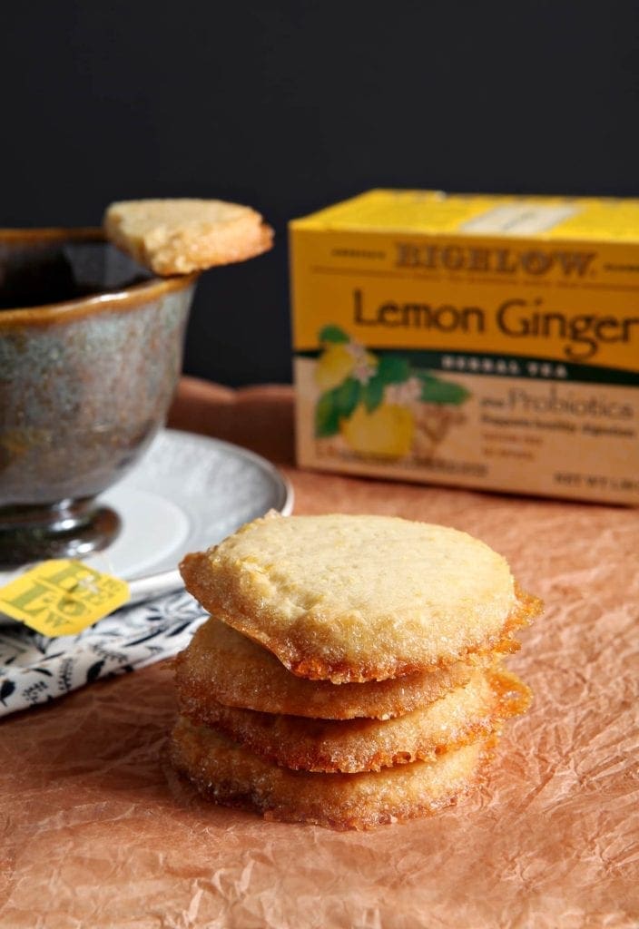 Stack of shortbread cookies in front of cup of tea and tea package 