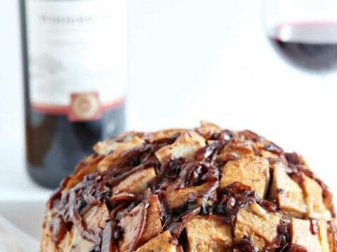 Cheesy French Onion Bread on plate in front of bottle of wine