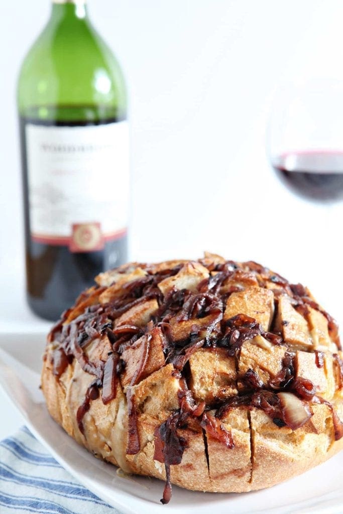 Cheesy French Onion Bread on plate in front of bottle of wine 