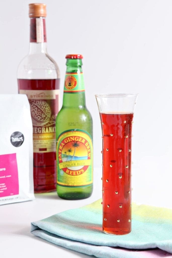 Bottles behind glass of ginger pomegranate experiment drink 