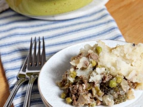 Piece of Shepard's Pie on white plate in front of yellow baking dish