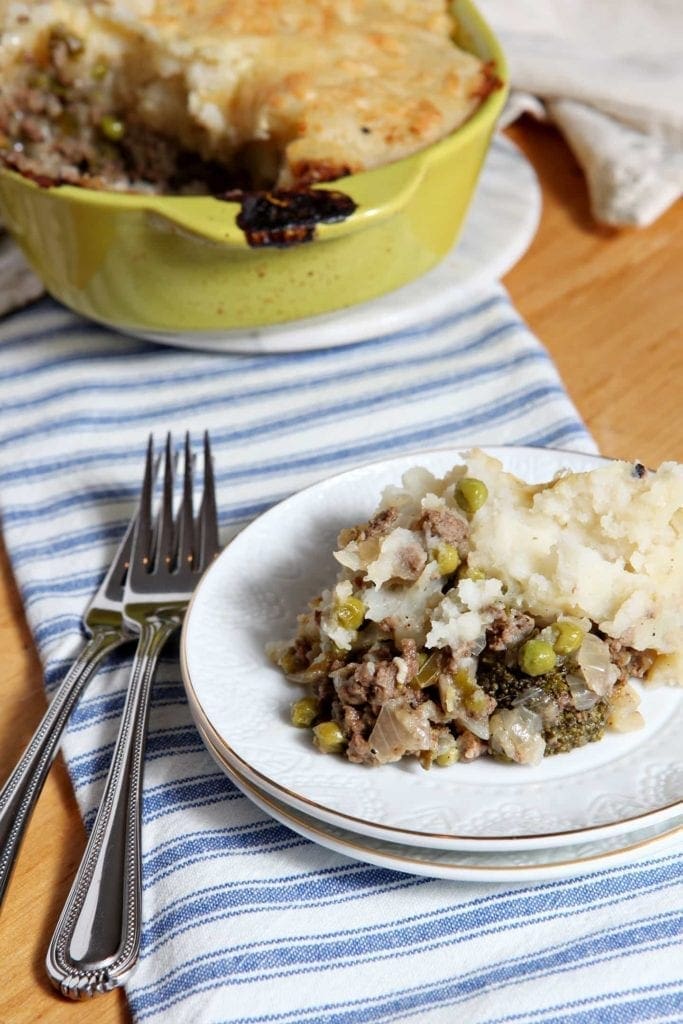 Piece of Shepard's Pie on white plate in front of yellow baking dish 
