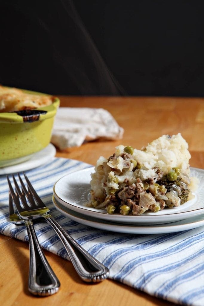 shepherds pie on two stacked white plates with forks