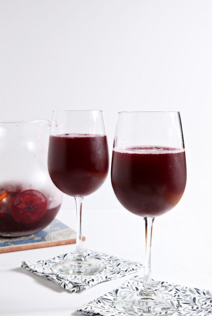 Two glasses of winter sangria next to glass pitcher 