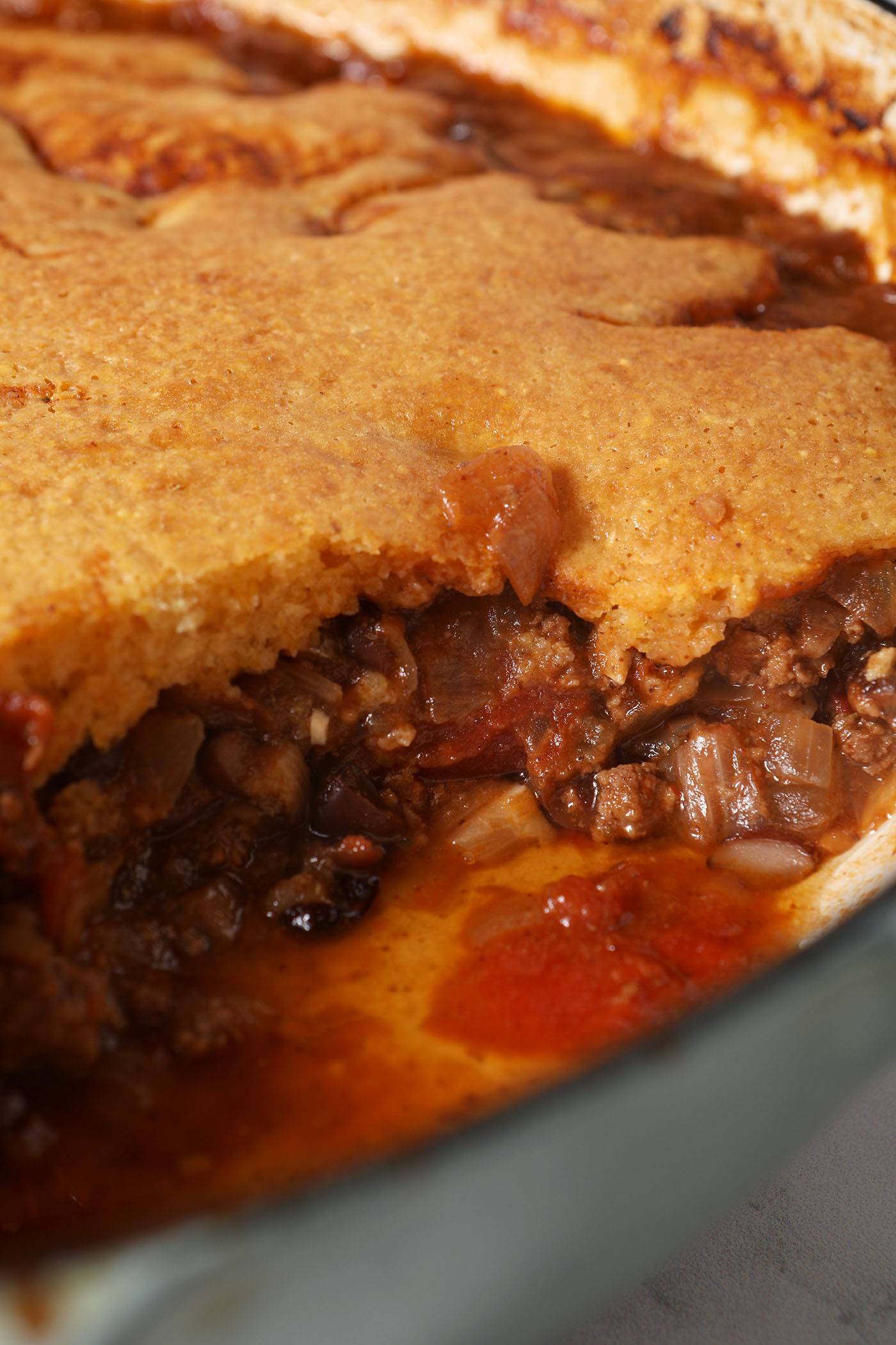 Side angle of a sliced-into Chili Cornbread Casserole in a pan