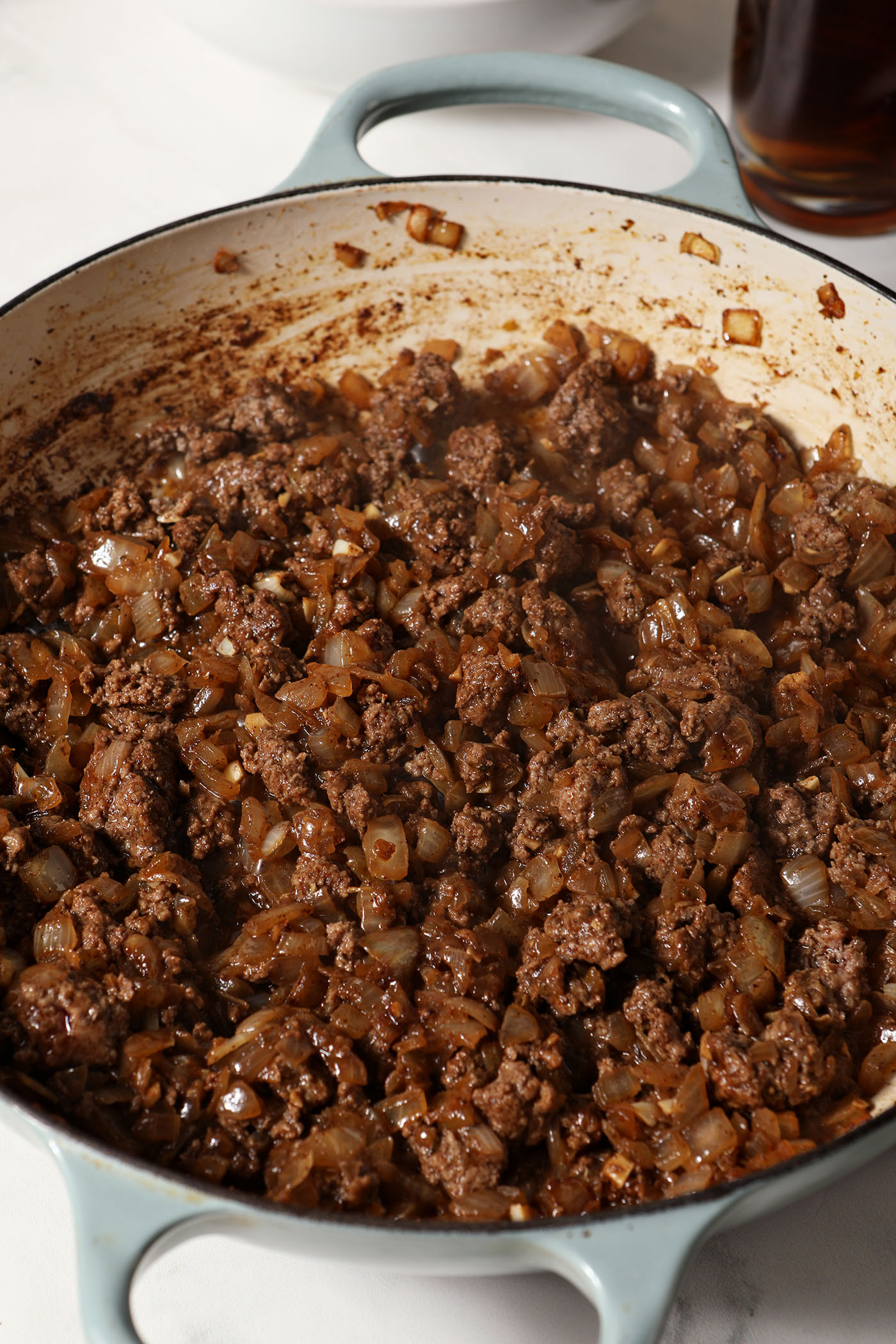 Cooked ground beef with onions and garlic in a braised pan on a marble surface
