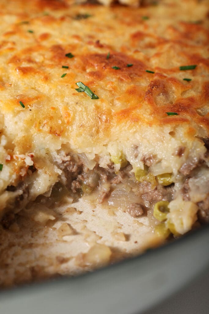 A close up of the side of cut-into cottage pie topped with cheesy potatoes