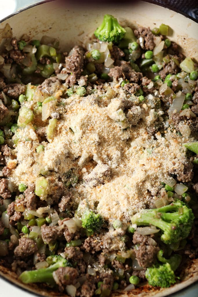 Breadcrumbs sprinkled on top of the meat mixture in a skillet