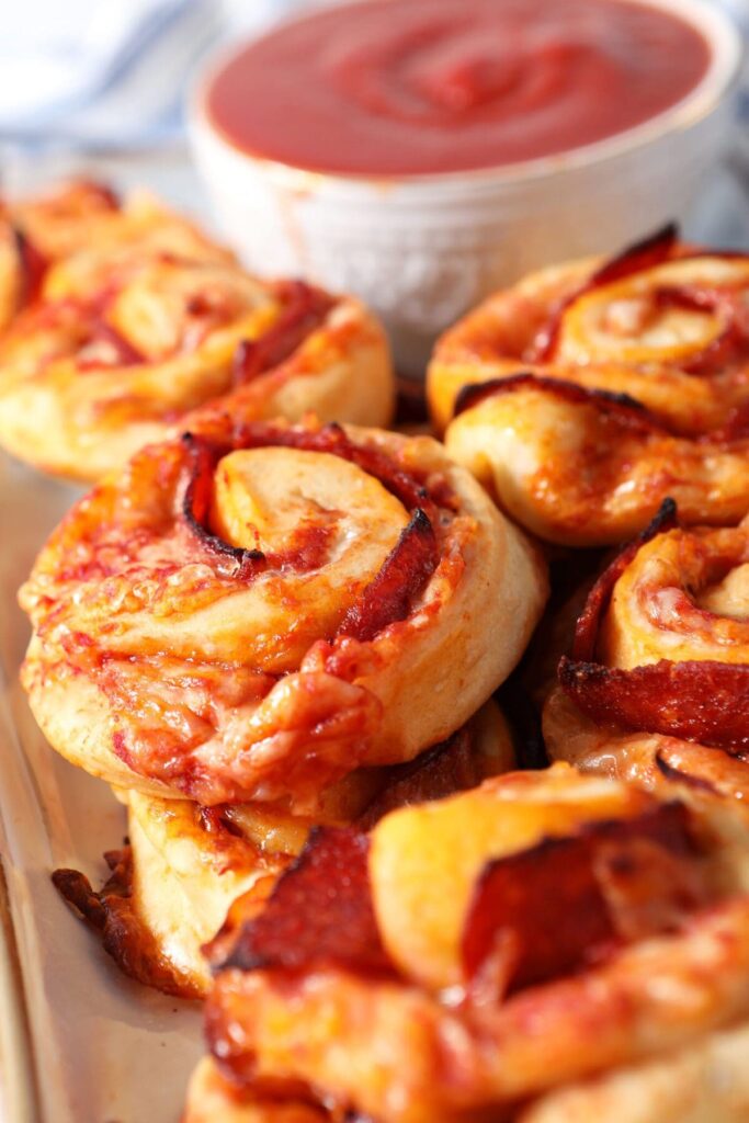 Close up of pizza rolls stacked on a platter with pizza sauce