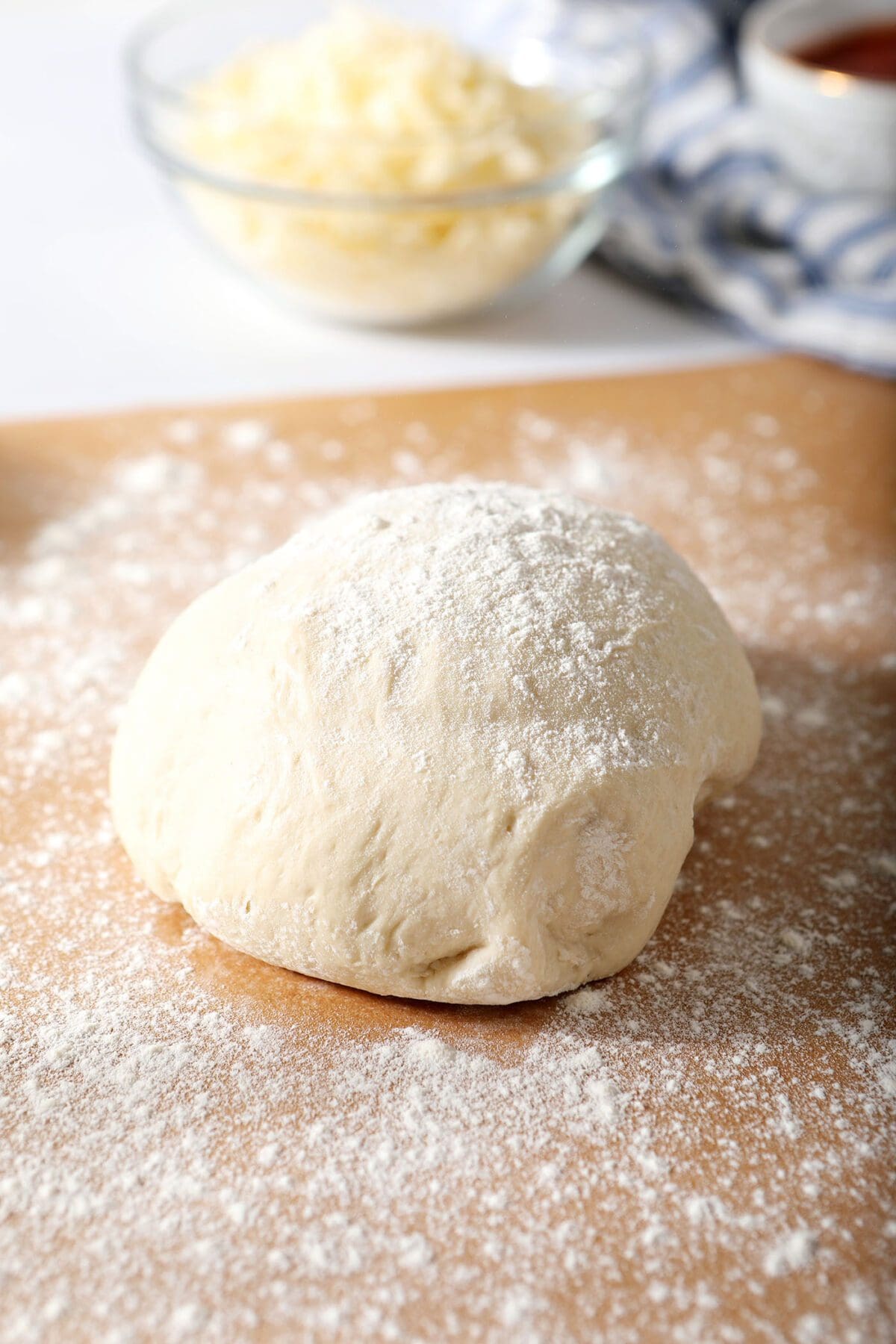 A ball of pizza dough on a sheet of parchment before rolling