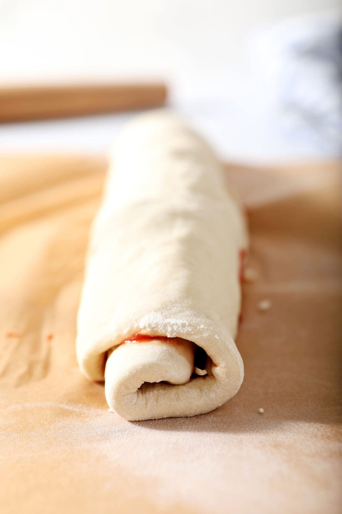 Rolled pizza dough on parchment before slicing into individual rolls