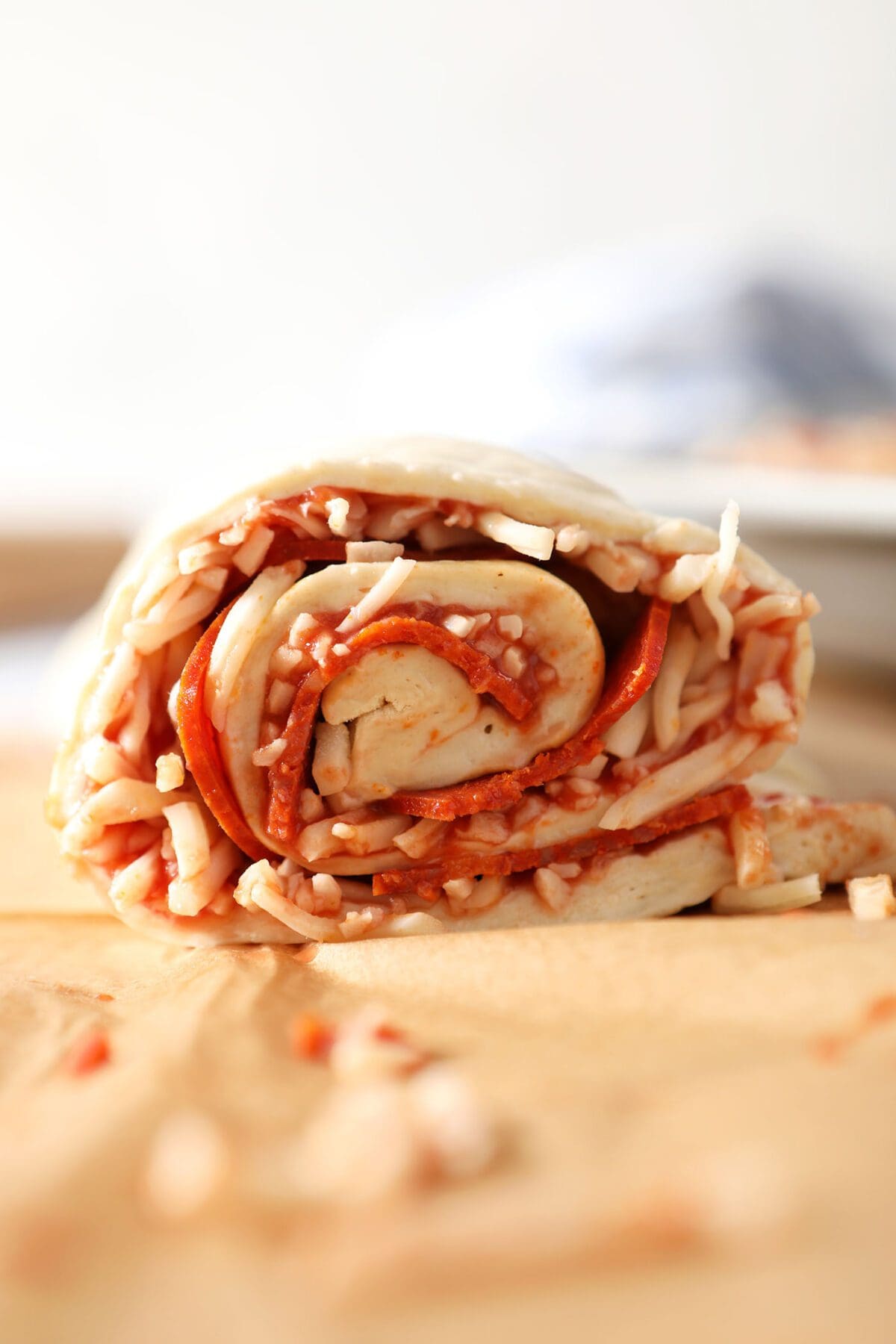 The inside of the rolled pizza roll dough with bits of cheese, pepperoni and sauce sticking out