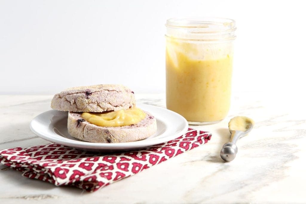 Glass jar of Orange Curd and spread onto sliced muffin 