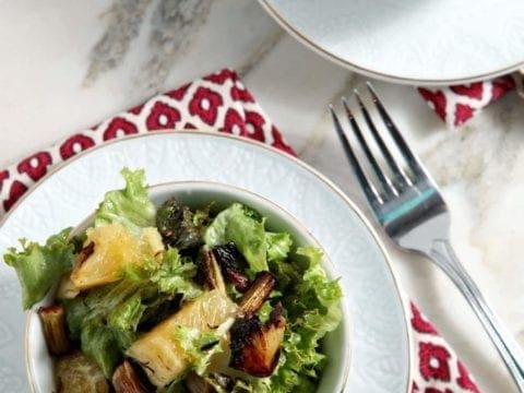 Overhead close up of roasted fennel orange salad in white bowl with fork