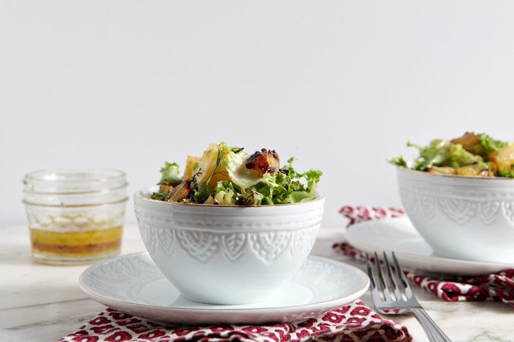 Two white bowls filled with roasted fennel orange salad with side of vinaigrette 