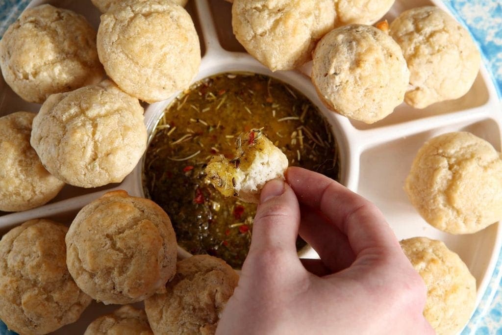 Hand dipping piece of bread in olive oil parmesan spice sauce 