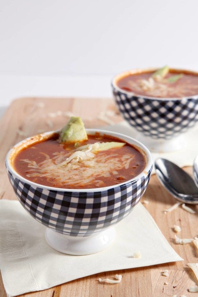 Two bowls of turkey taco soup in blue checked bowls on wood