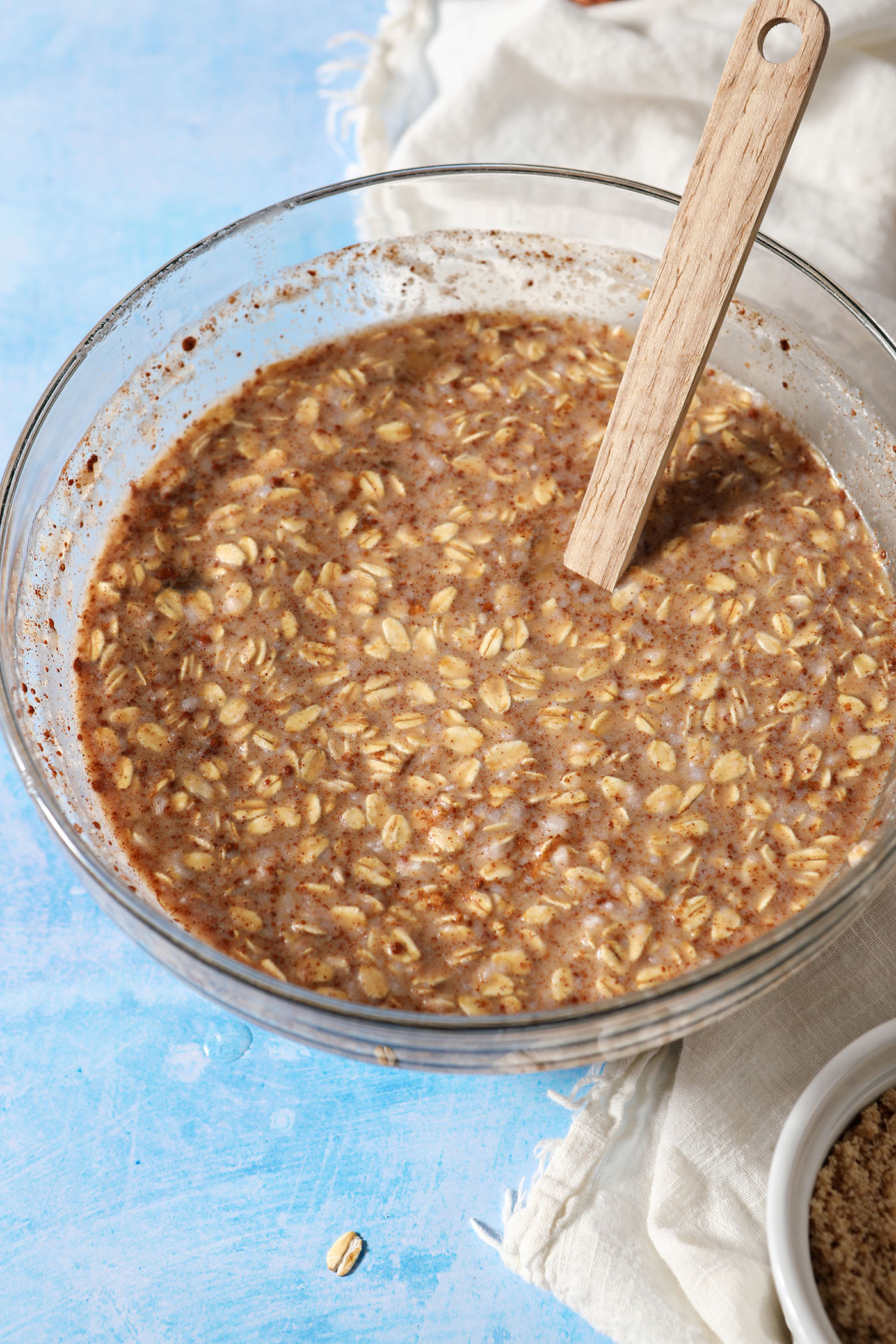 Mixed ingredients for baked oatmeal bars in a bowl on a blue surface